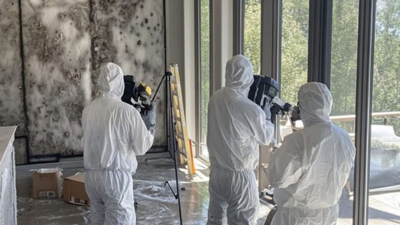 Remediation crew in protective suits working in a large room